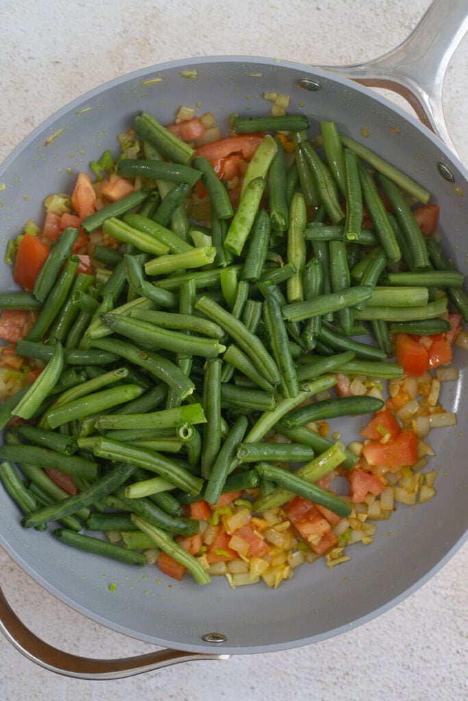 Bodu beans added to aromatics in a frying pan.