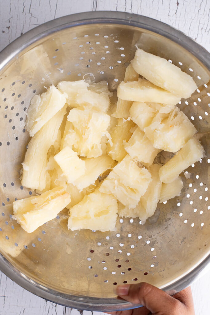 Boiled cassava root in a silver colander.