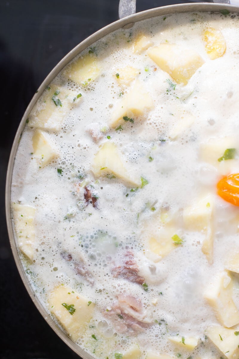 Layering of coconut milk and fresh herbs over salted meat.