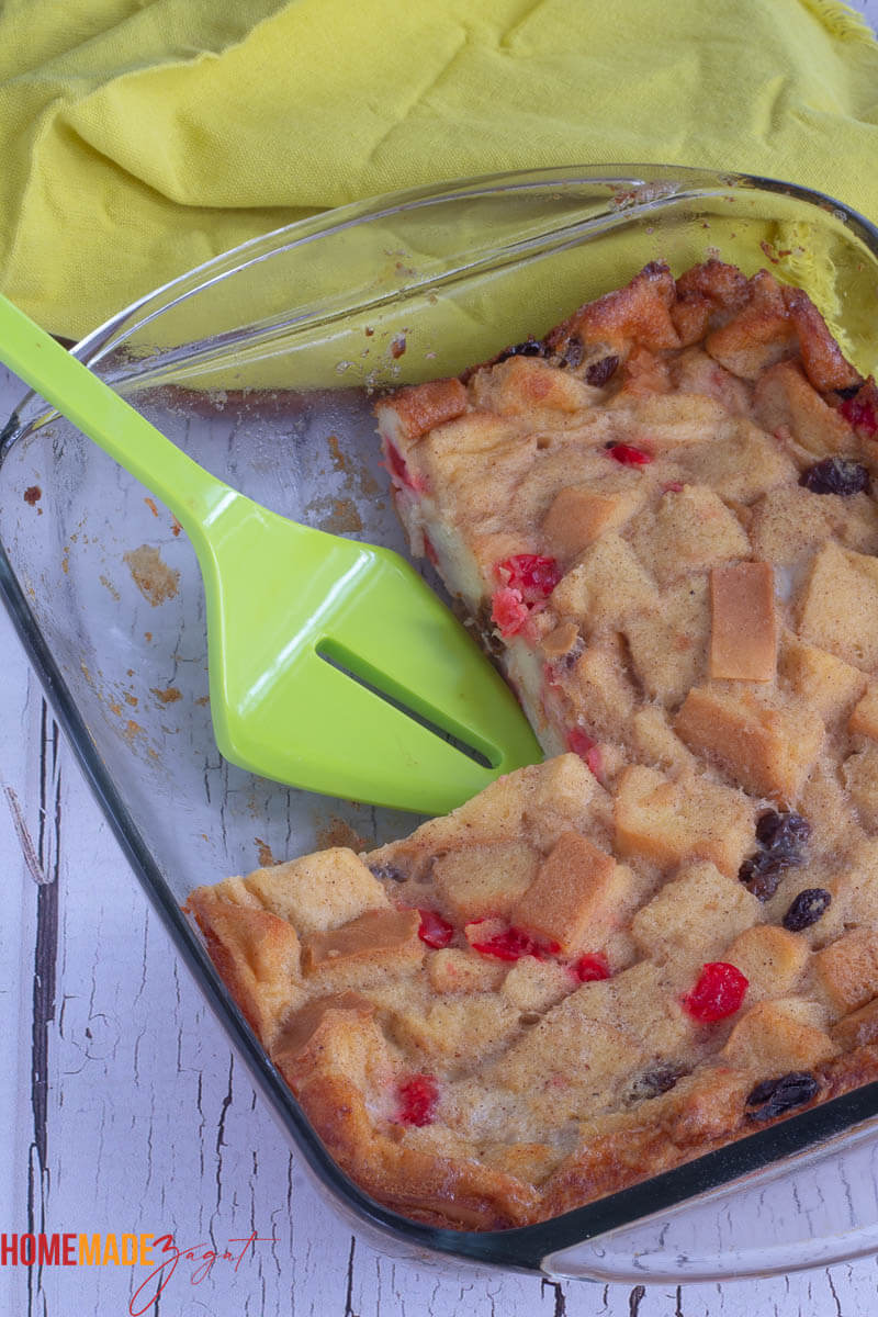 Pan of bread pudding with one slice out, and a green spatula
