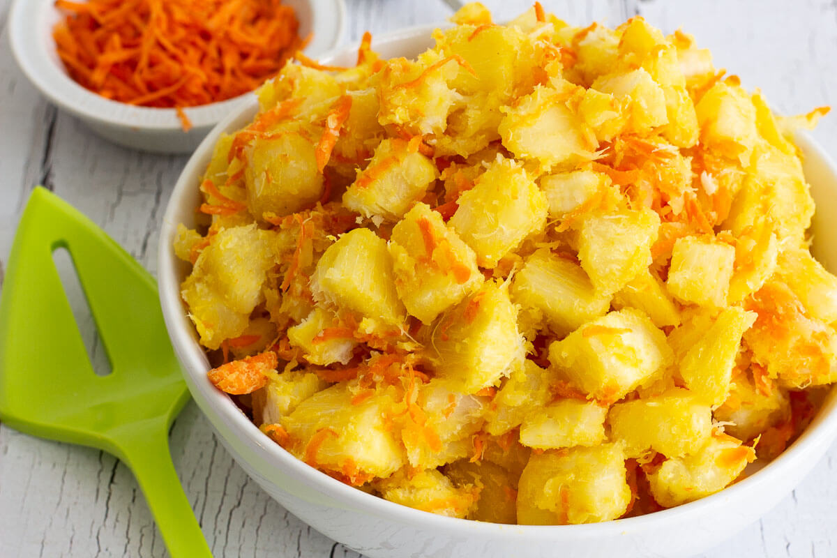 Cassava with butter and carrots in a white bowl.