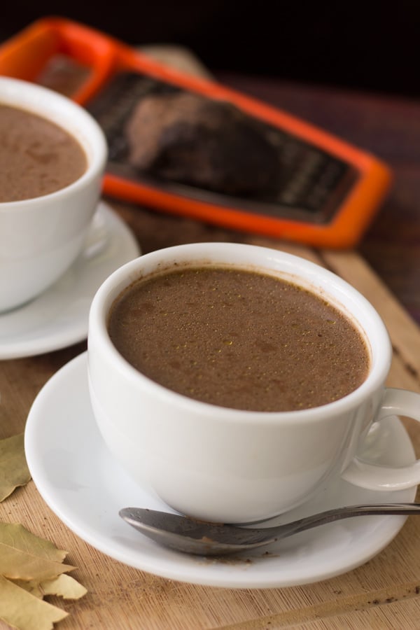 Caribbean Cocoa Tea in White Cups with Cocoa Balls and Grater in the Background.