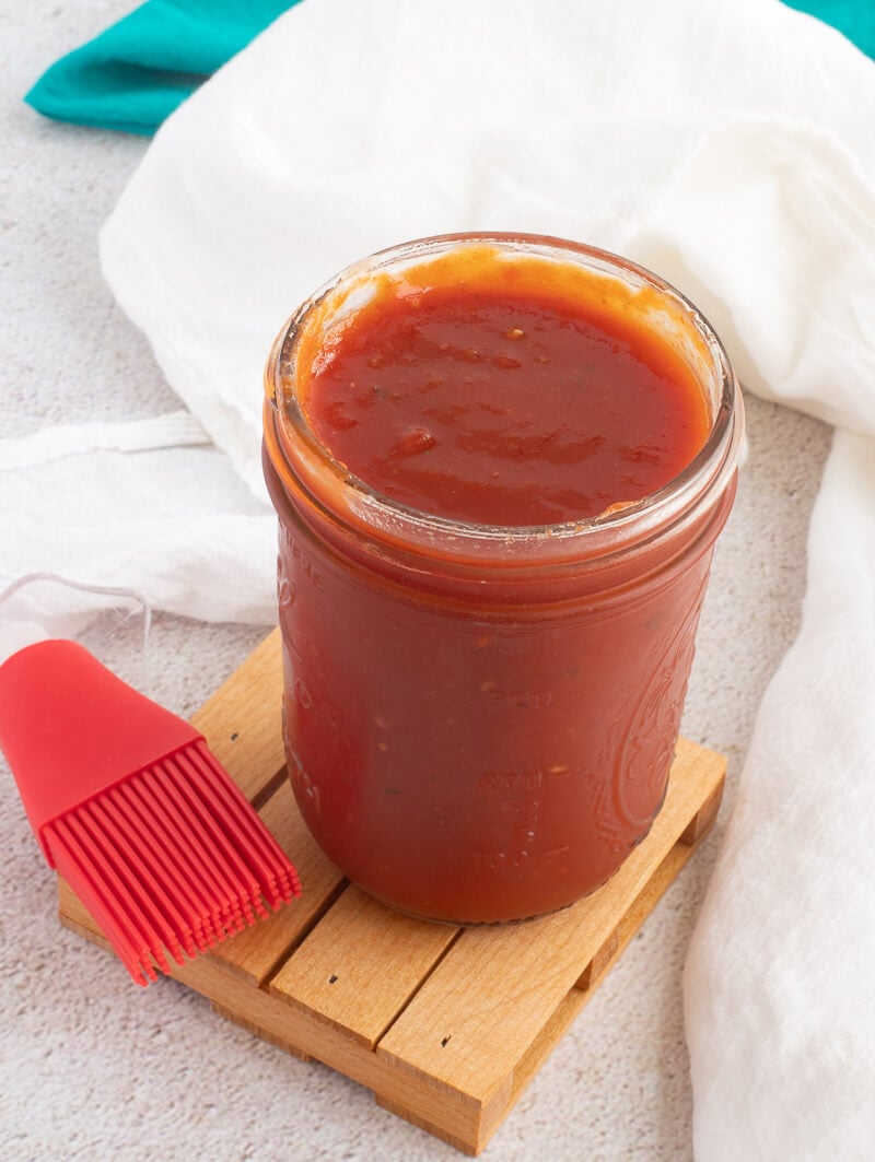 Finished Caribbean bbq sauce in a jar with a silicone brush.