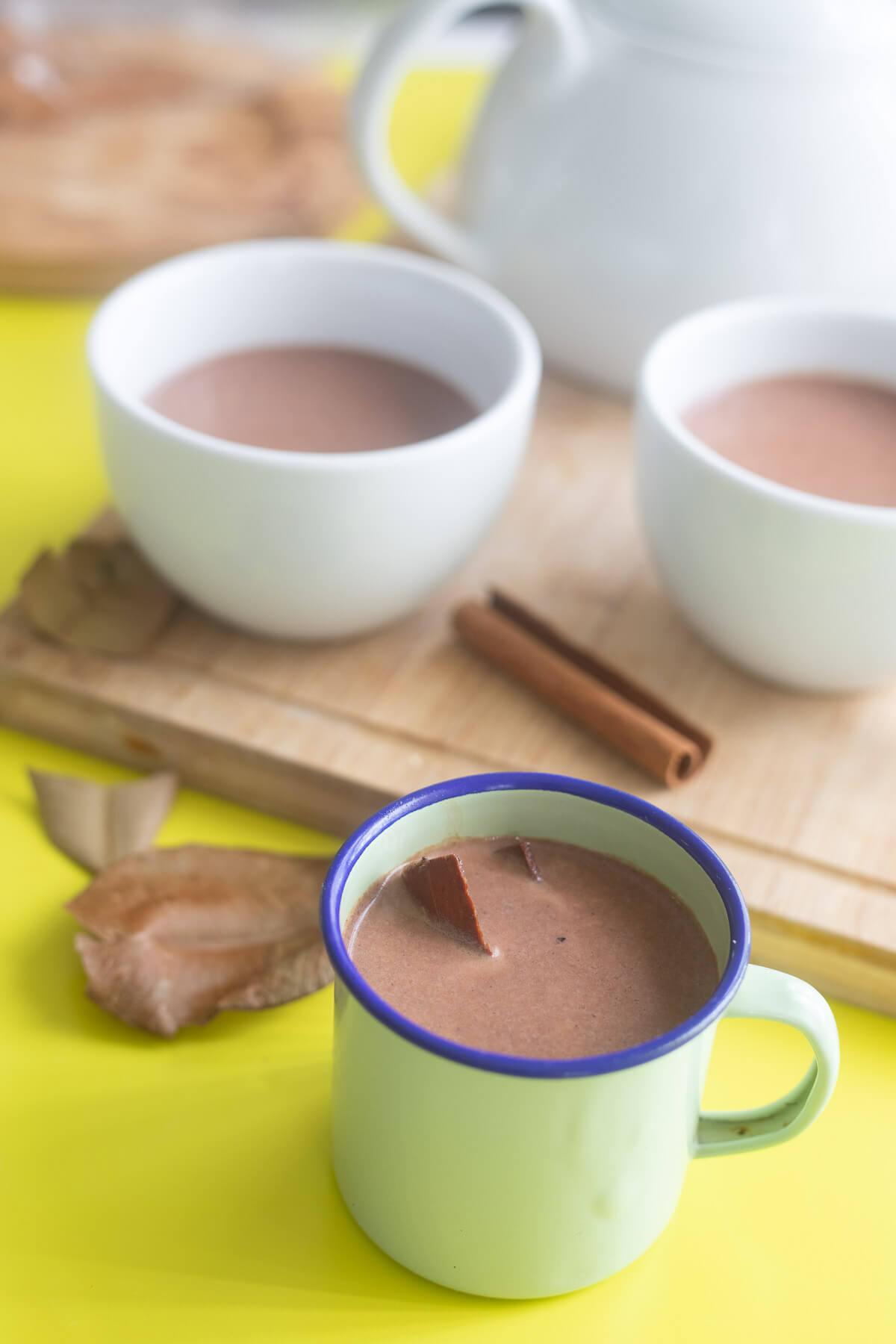 Enamel Cup of Caribbean Cocoa Tea with Two White Mugs in the Background.
