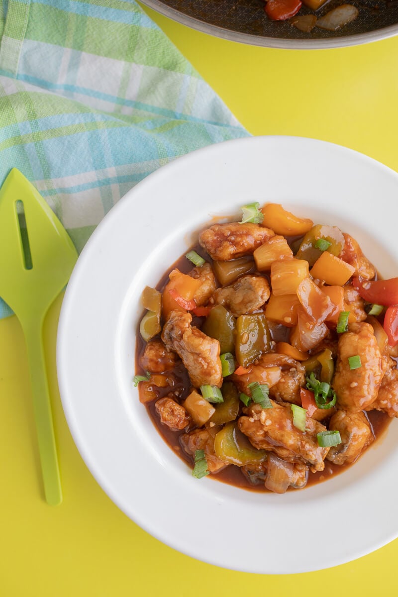 A white bowl full of sweet and sour fish on a yellow background.