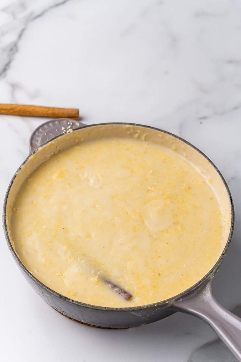 Boiling pot of cornmeal porridge with milk and spices.