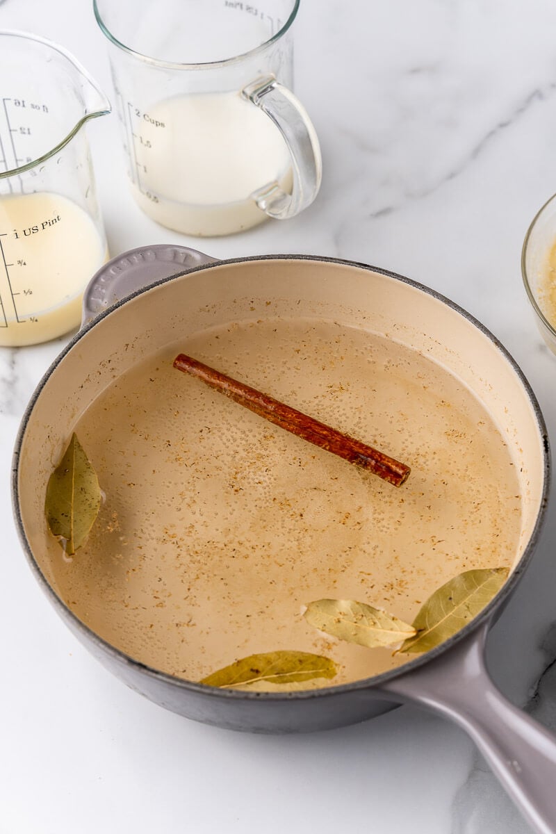 A pot of boiling water with spices of bay leaves, cinnamon and nutmeg.