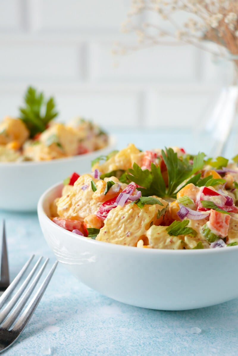 A finished bowl of potato salad garnished with parsley.