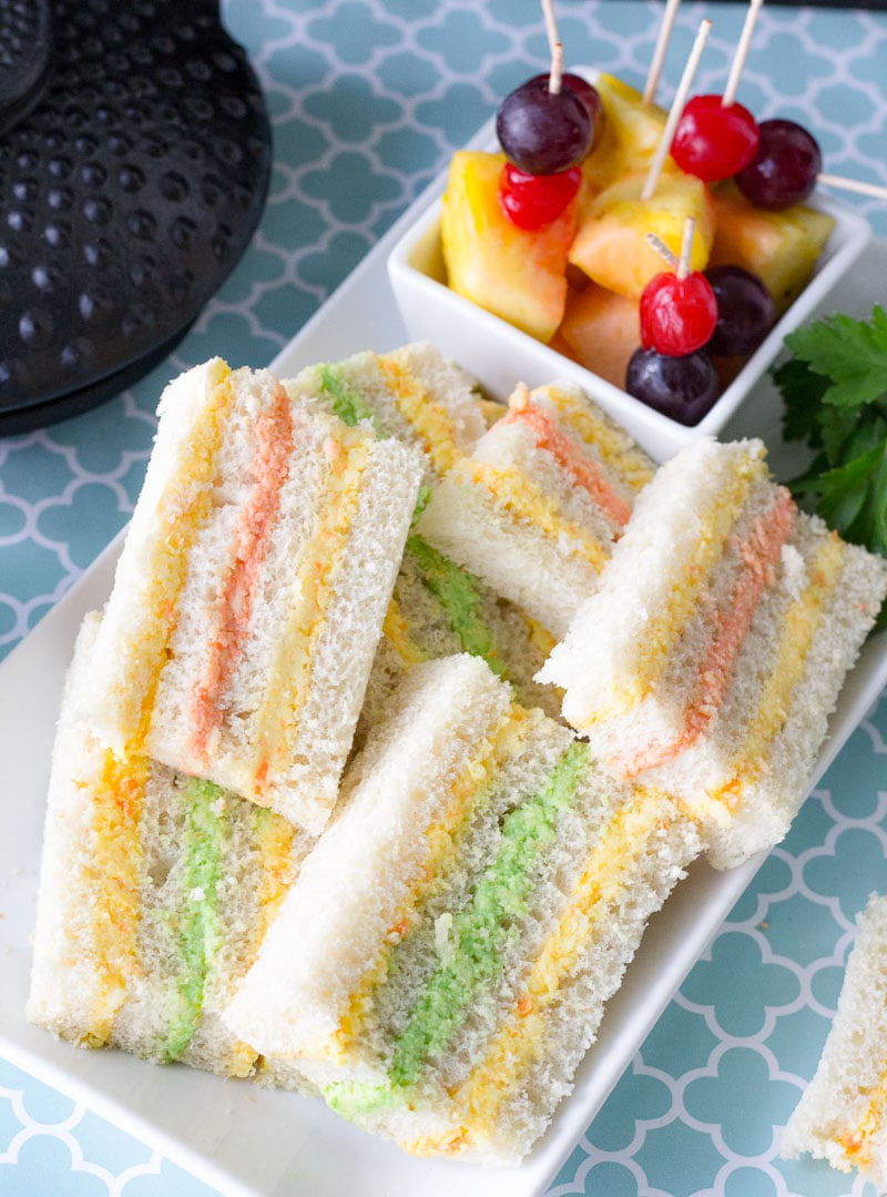 Layered cheese paste sandwich with fruits and tea cup.