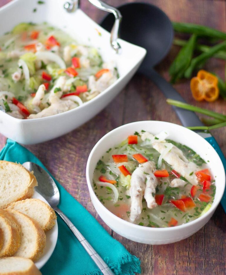 Chicken foot souse in white serving bowls with bread on the side.