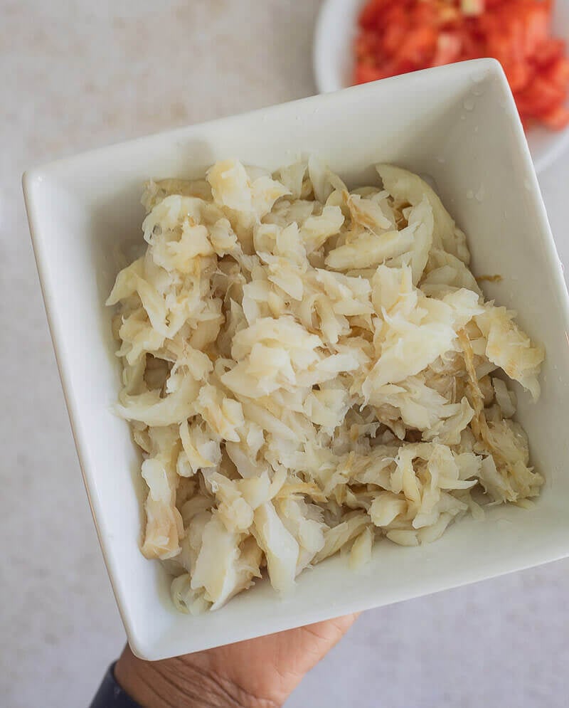 Chipped up saltfish in a white bowl, ready to be used to cook.