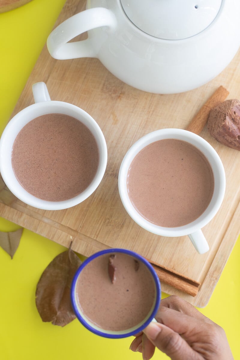 Enamel cup and white mugs filled with chocolate tea.
