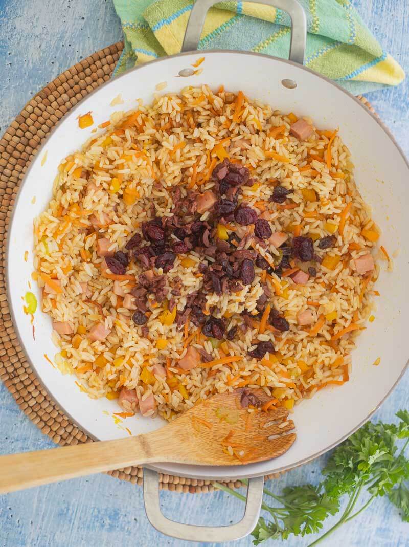 Rice added to sauteed vegetables and mixed in with black olives, with raisins and cranberries.