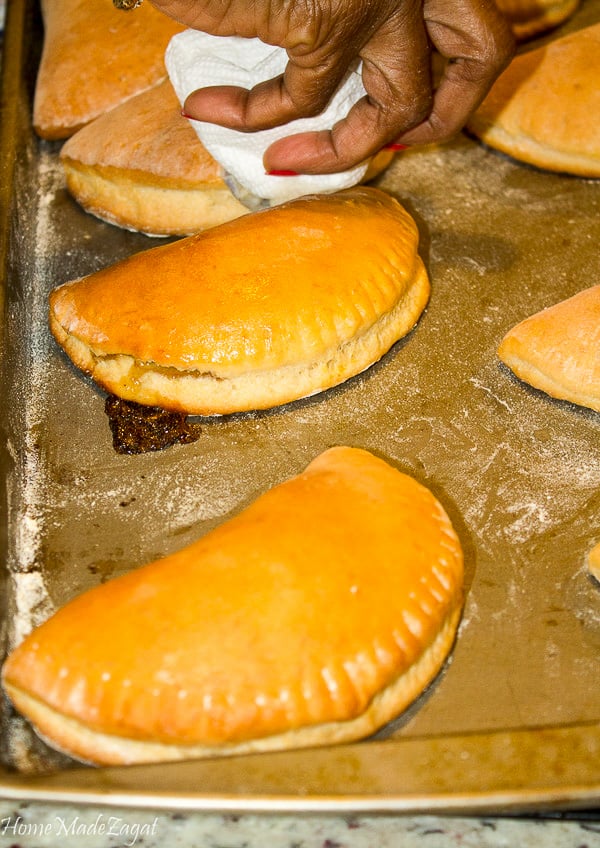 A picture of a hand adding glaze to coconut tarts.