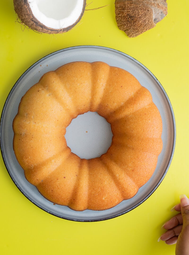 Baked coconut cake on a blue plate on a yellow background.