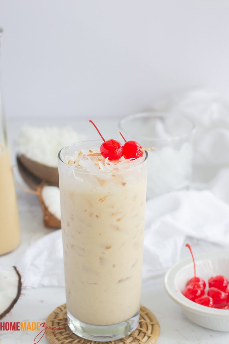 A filled glass of ice with coconut Ponche de creme with two cherries on top