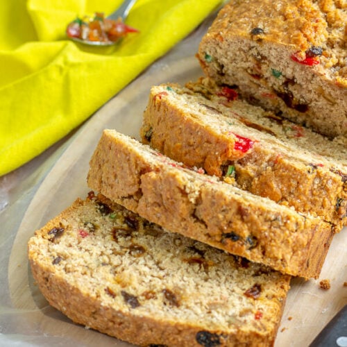 A loaf of Coconut sweet bread with a few slices, and a spoon of mixed peel