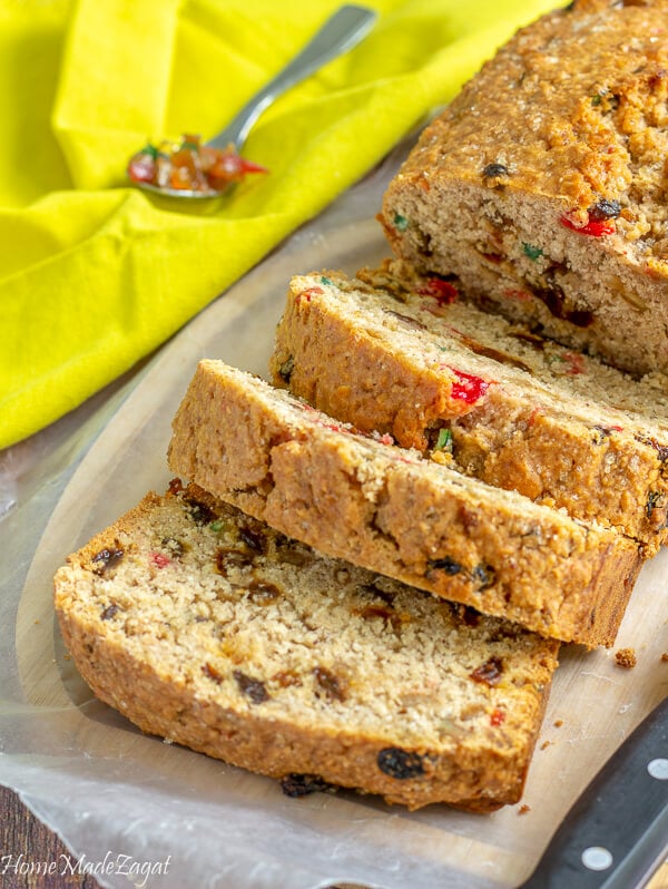 A loaf of Coconut sweet bread with a few slices, and a spoon of mixed peel