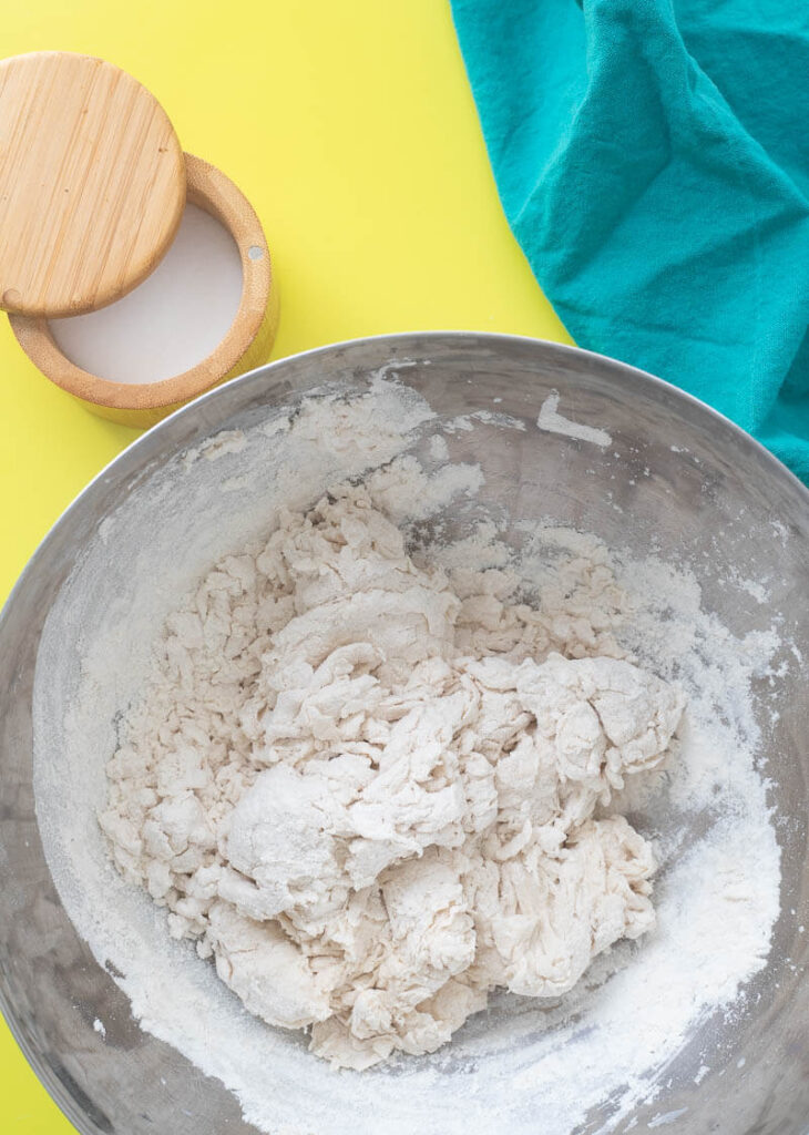 Combining water and flour to make a smooth dough.