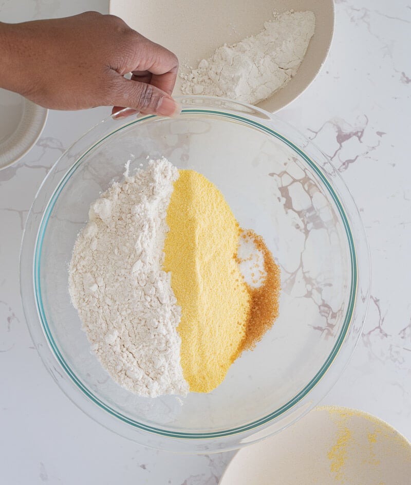 The dry ingredients for making cornmeal dumplings in a glass bowl ready to be mixed.