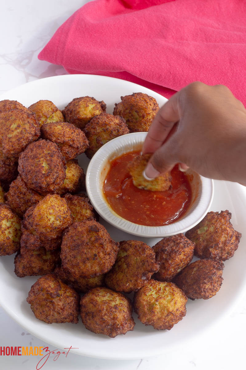 Dipping a fritter into bowl of dipping cocktail sauce