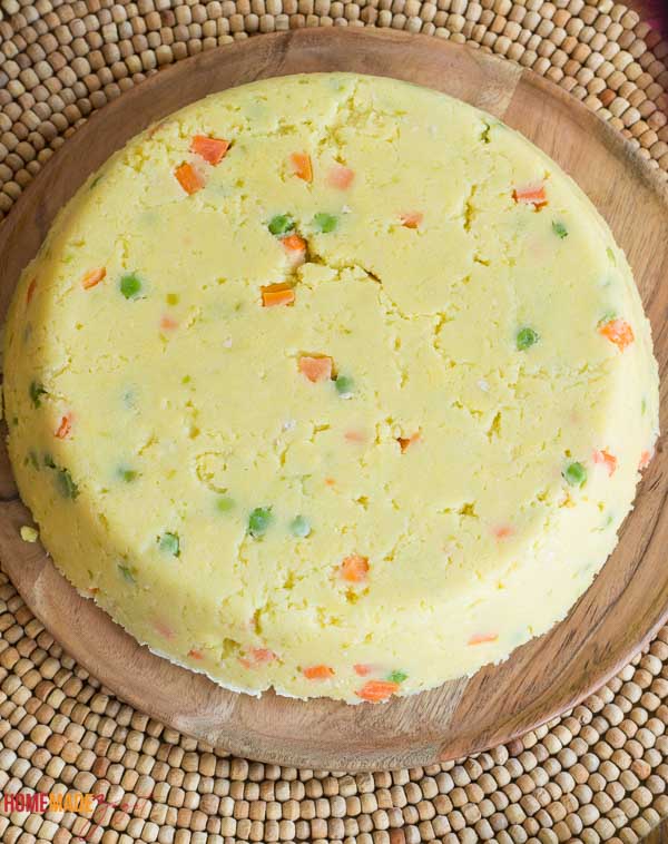 A completed bowl of cornmeal coo coo on a brown plate.