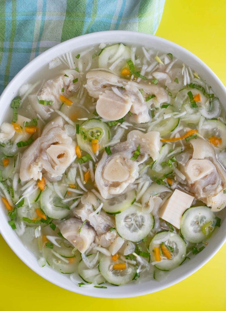 A large bowl of cow heel souse with a checkered napkin on a yellow background.