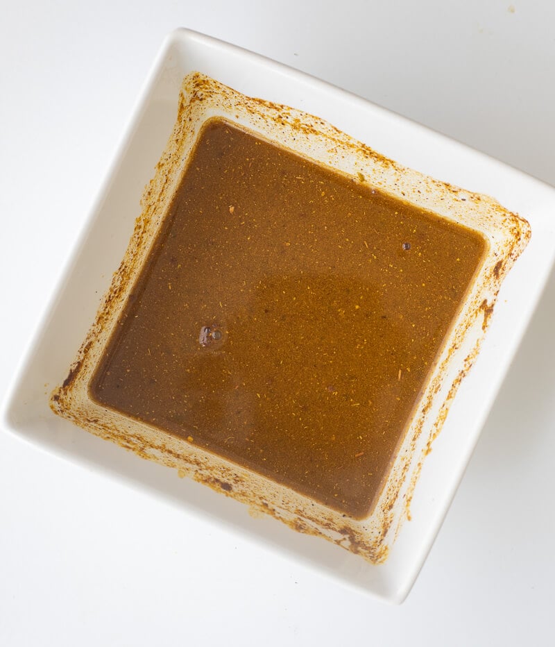 A white bowl with a mix of curry and other spices to make a curry paste.