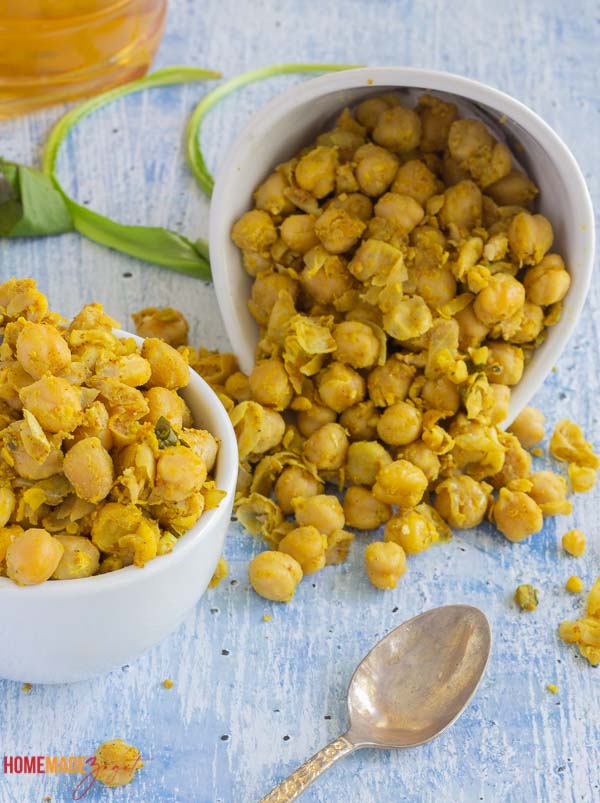 A cup and a jar of cooked curry chicpeas spread falling out of jar