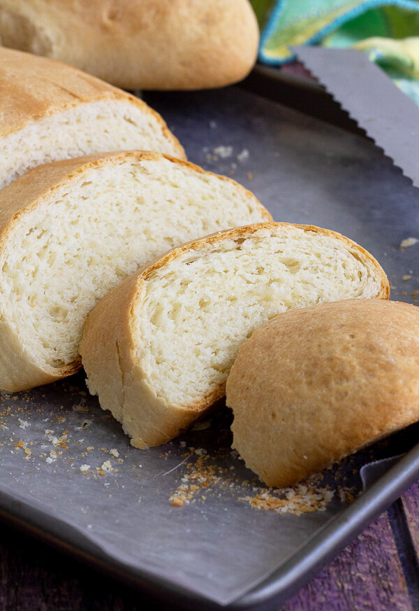 Slices of butter bread in a tray with a loaf in the background.