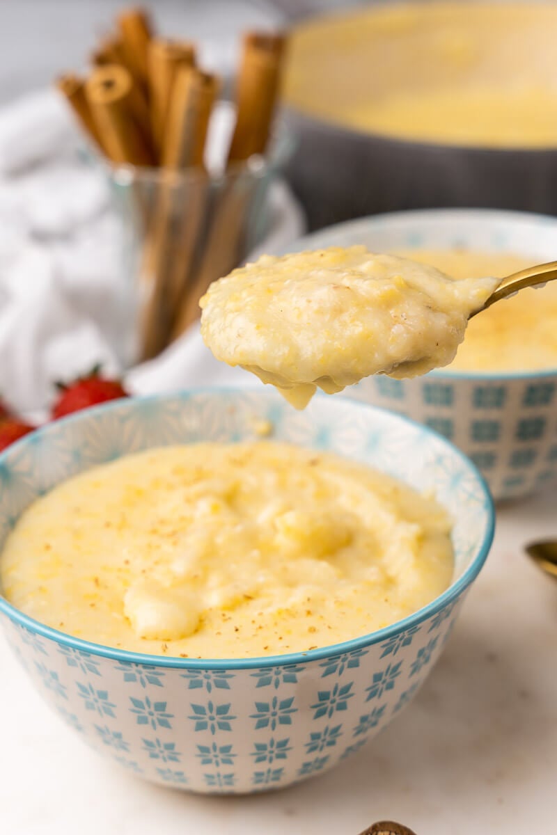 A full spoon of cornmeal porridge over a bowl of porridge.