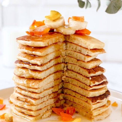 Cassava pancakes stacked with maple syrup and fruit toppings.
