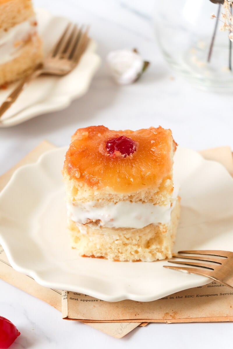 Direct shot of a slice of pineapple upside down cake with whipped creme in the center