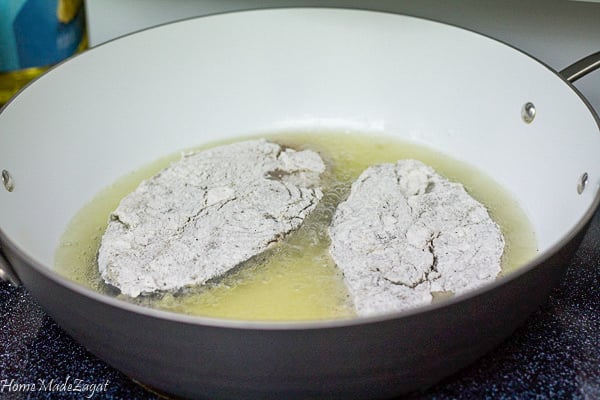 Floured slices of fish in a pot of oil frying