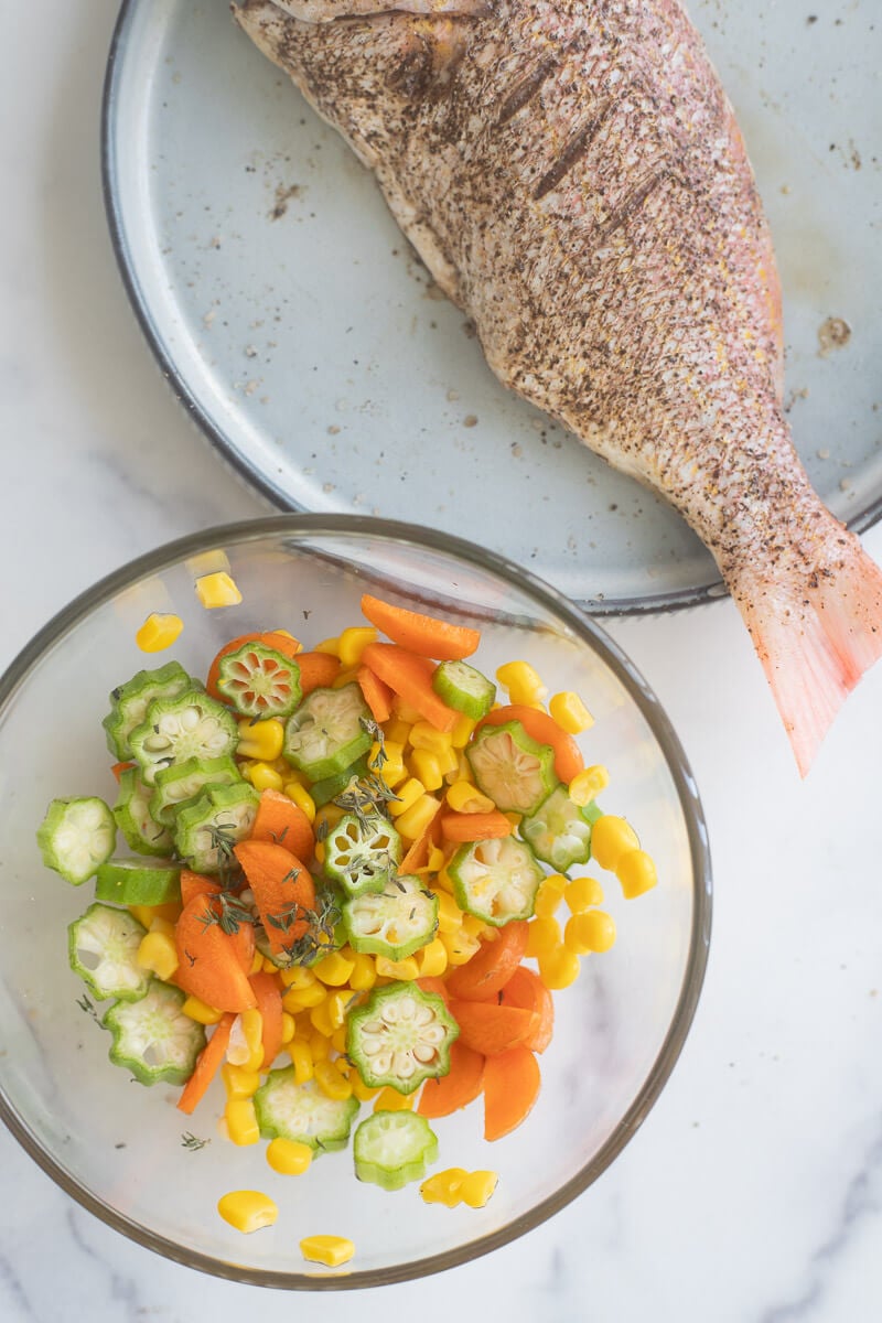 Clear bowl full of filling mixture and seasoned fish in the background.