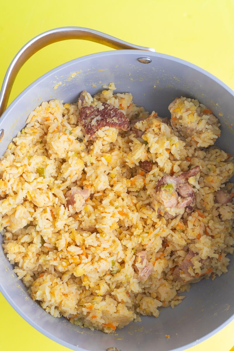 Split peas and rice steamed till the rice is cooked in a deep pot on yelow background.