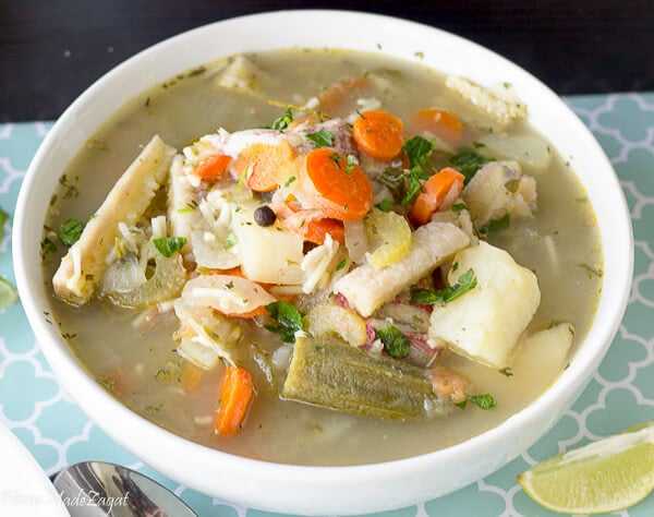A full white bowl full of ground provision and fish and other veegetables.
