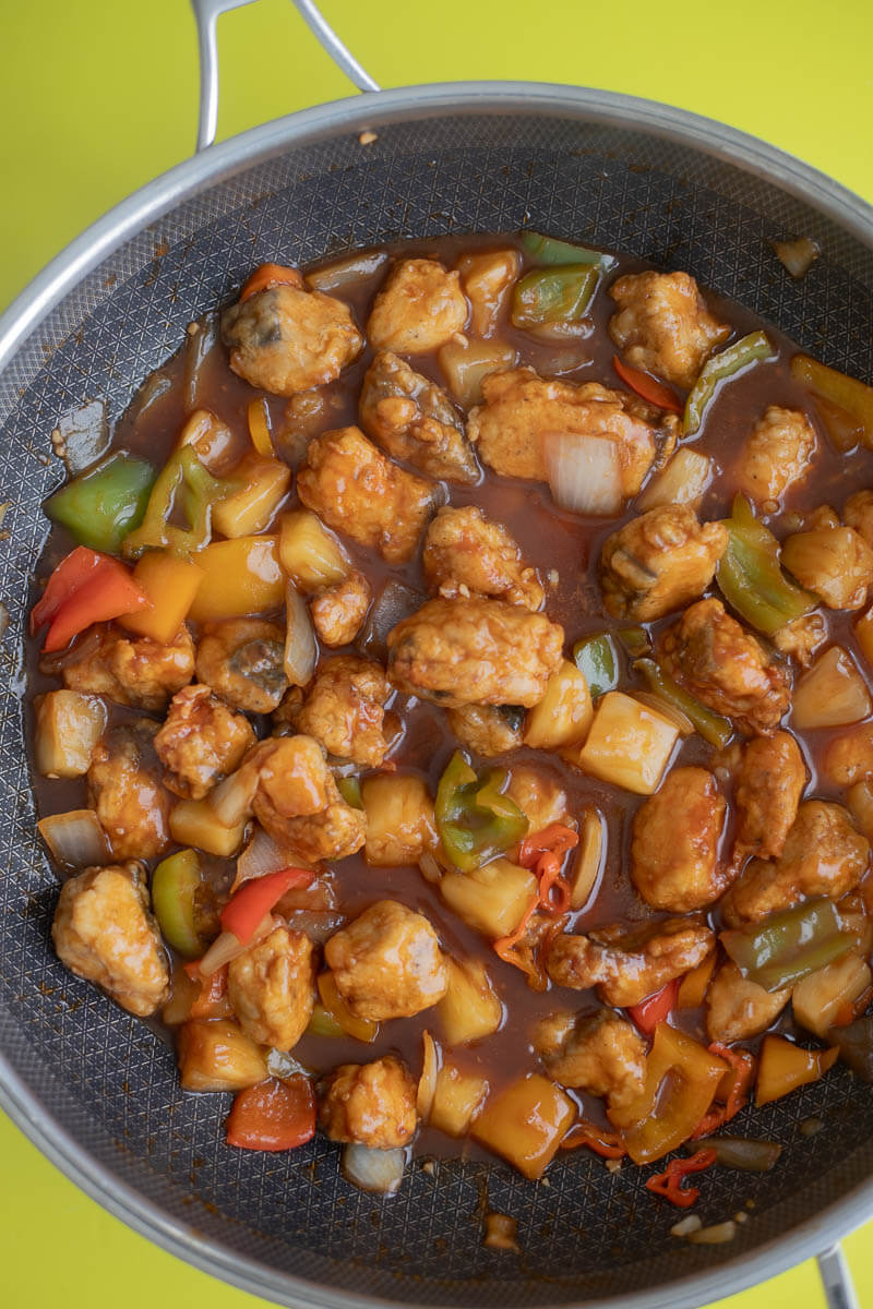 Sweet and sour sauce with the fried king fish bites added in the wok.
