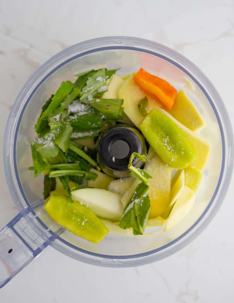 All the ingredients needed to make mango chutney in the food processor on a white backdrop.