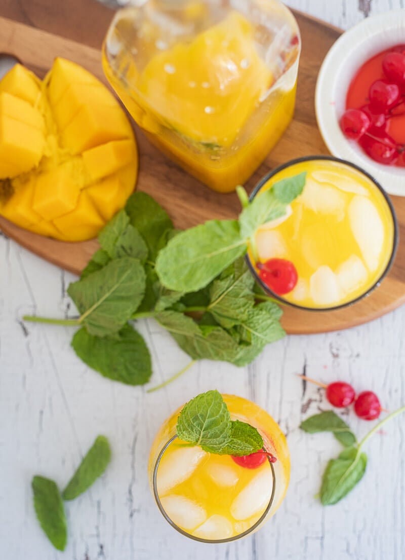 Overhead view of mango juice poured into glasses with mint garnish.