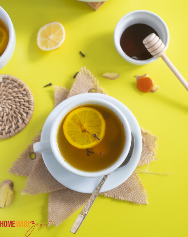 Top view of a mug of turmeric ginger lemon tea in a white tea cup