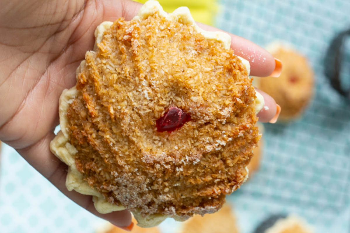 Holding up a gizzada to showcase the shell and the filling.