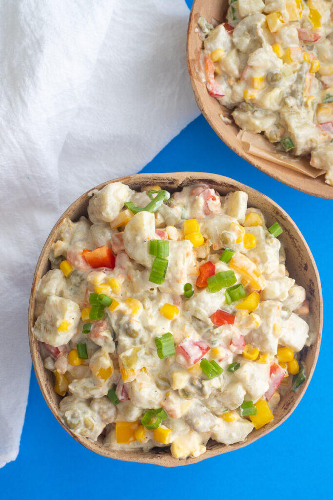 Creamy green banana salad with herbs in a brown calabash.