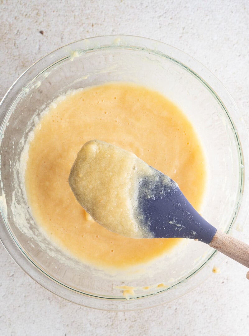 Guava puree in a large bowl with a purple spatula showing the consistency.