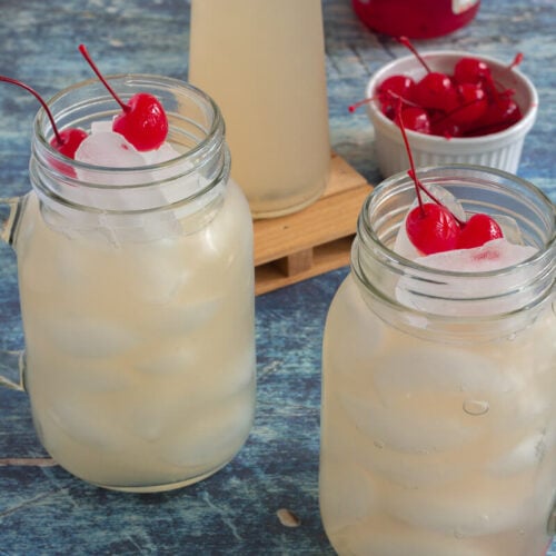 Mason jars packed with ice and guava fruit juice and topped with cherries