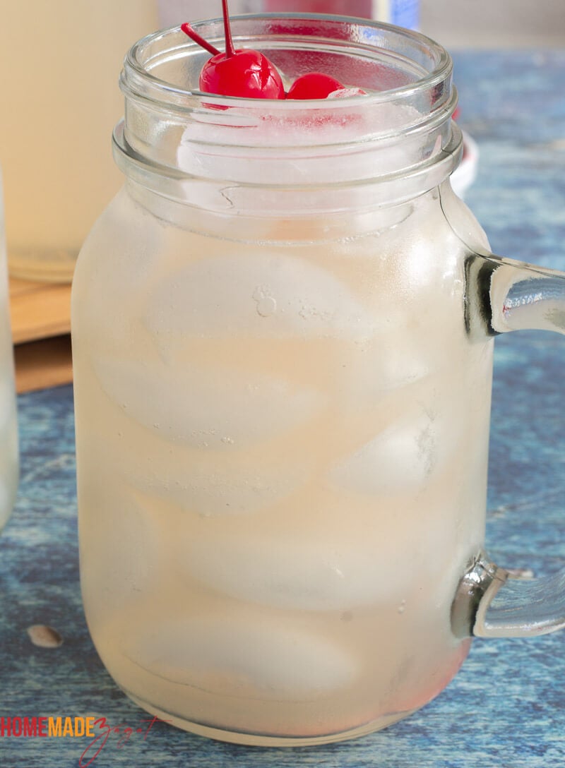 close up of a mason jar of guava juice with ice and cherries