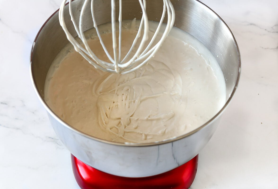 Blended guinness and milk mixture with the heavy whipped cream in a bowl with a silver whisk.