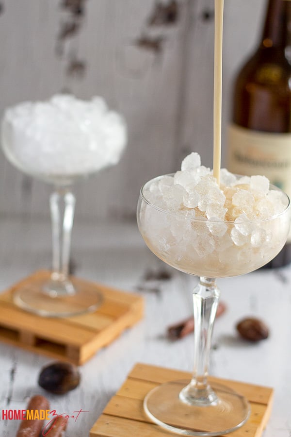 Pouring mixed Haitian cremas into a clear glass with ice.