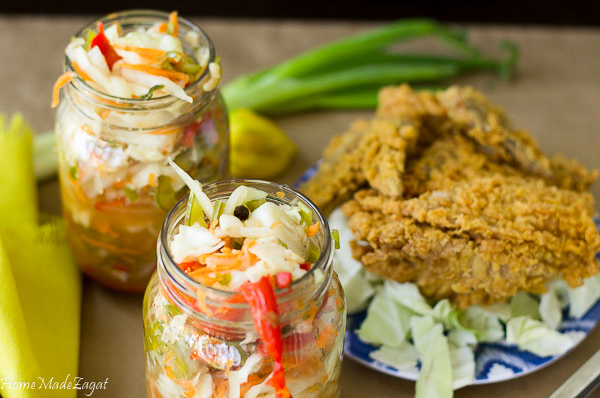 Bottles of pikliz with some fried chicken in the background.