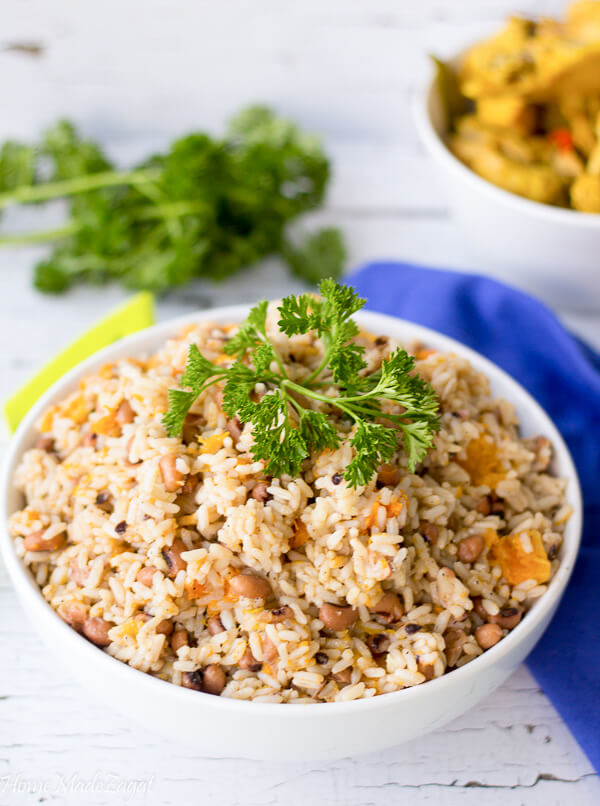 A finished pot well cooked black eyed peas and rice alongside some fish.